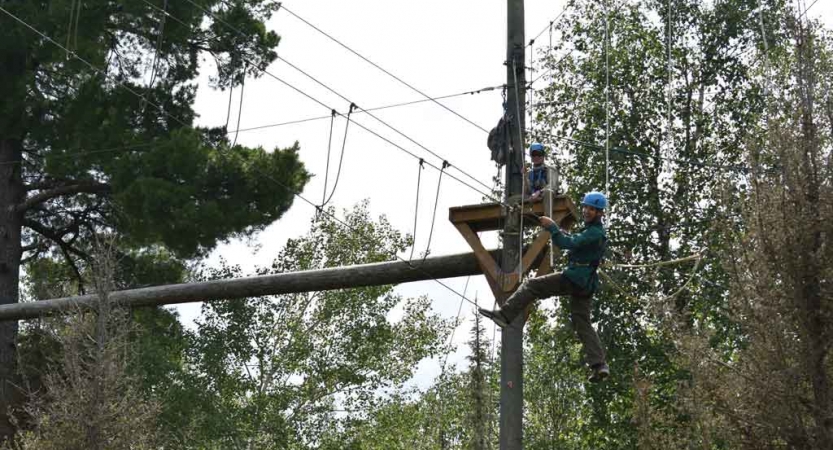 a student balances on ropes while participating in a high ropes course with outward bound